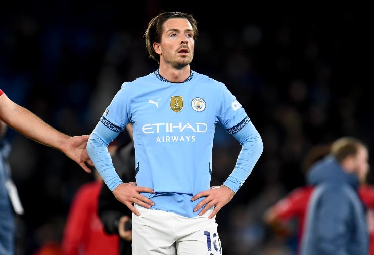 Jack Grealish con le mani sui fianchi al centro del campo